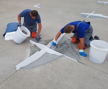 Several employees in work clothes working with mortar on asphalt